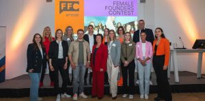 Gruppenfoto mit Teilnehmerinnen, Jury und Organisator:innen des Female Founders Contest Mecklenburg-Vorpommern 2026 vor einer Bühne mit Event-Logo in der IHK zu Schwerin
