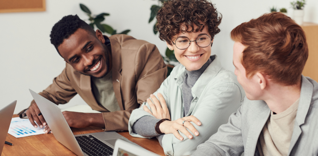 3 Personen sitzen nebeneinander an einem Tisch