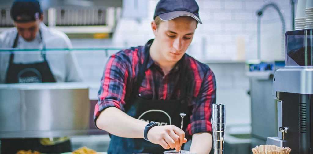 Junge Person arbeitet in einer Großküche